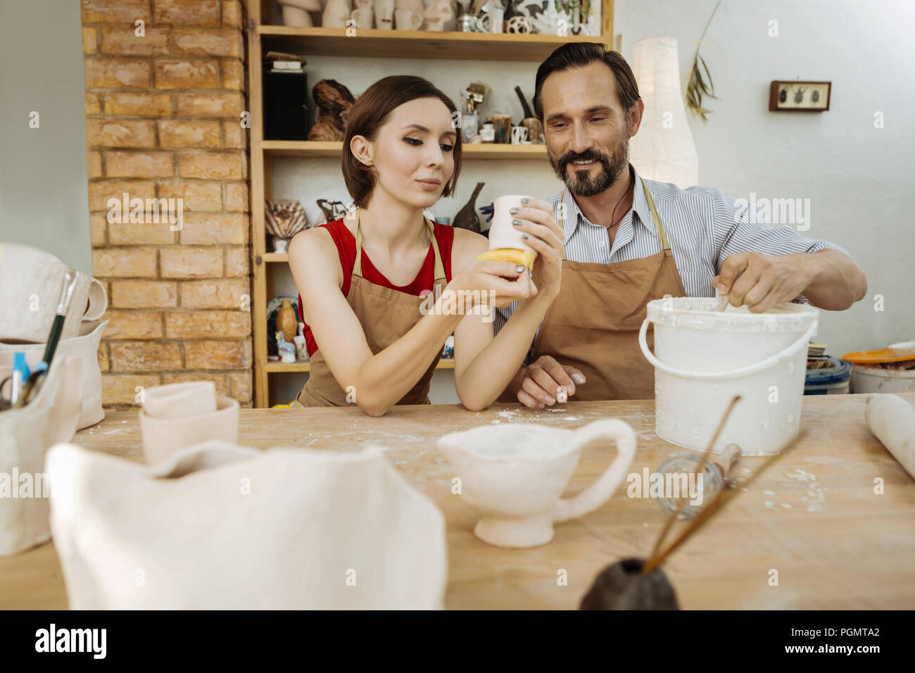 Couple of ceramists sitting at the table making their handiworks Stock Photo