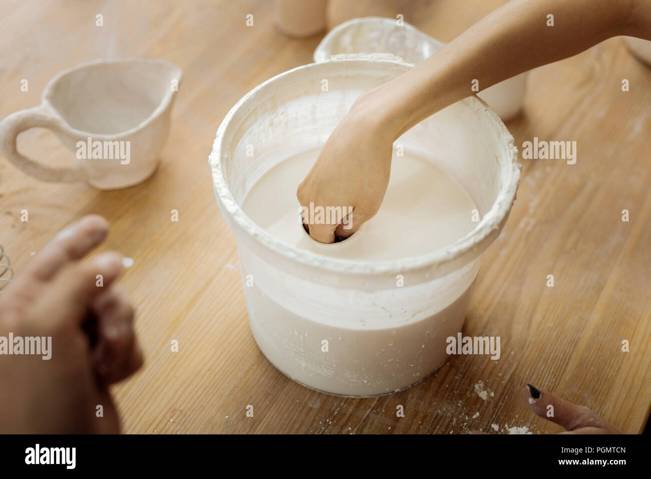 Female potter putting her hand in clay substance Stock Photo