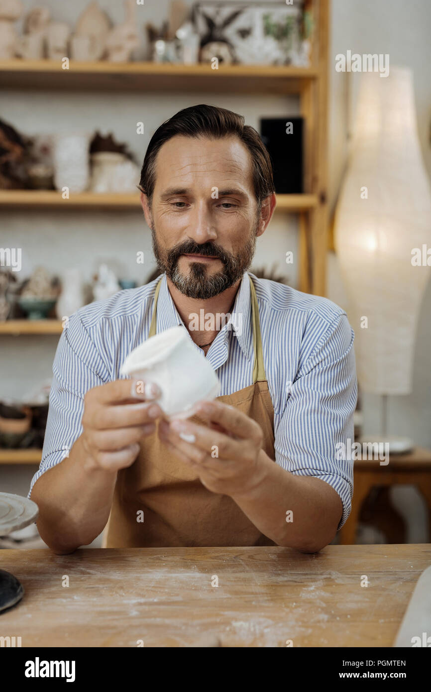 Bearded potter with facial wrinkles working in workroom Stock Photo