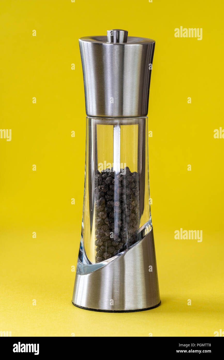 Stainless steel and glass pepper mill isolated on a yellow background