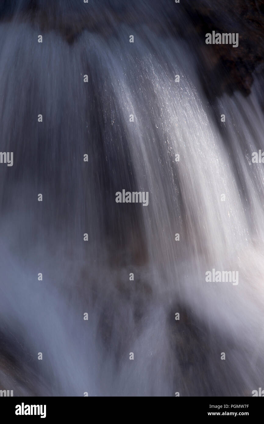 Small waterfall with blurred movement catching the sunlight Stock Photo