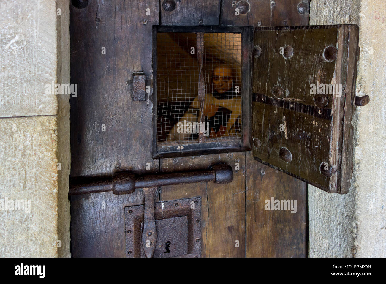 Heavy wooden medieval prison cell door with open hatch showing prisoner in the Château de Bouillon Castle, Luxembourg Province, Ardennes, Belgium Stock Photo