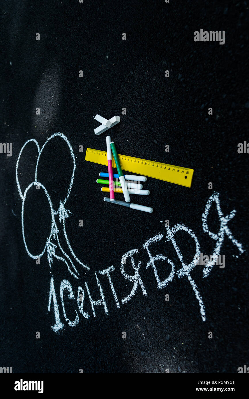 white chalk on black asphalt inscription in Russian September 1. yellow line, colorful markers, painted balls Stock Photo