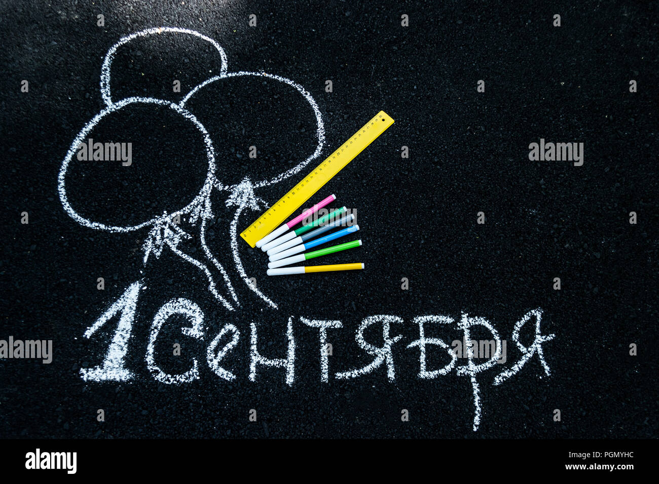 white chalk on black asphalt inscription in Russian September 1. yellow line, colorful markers, painted balls Stock Photo