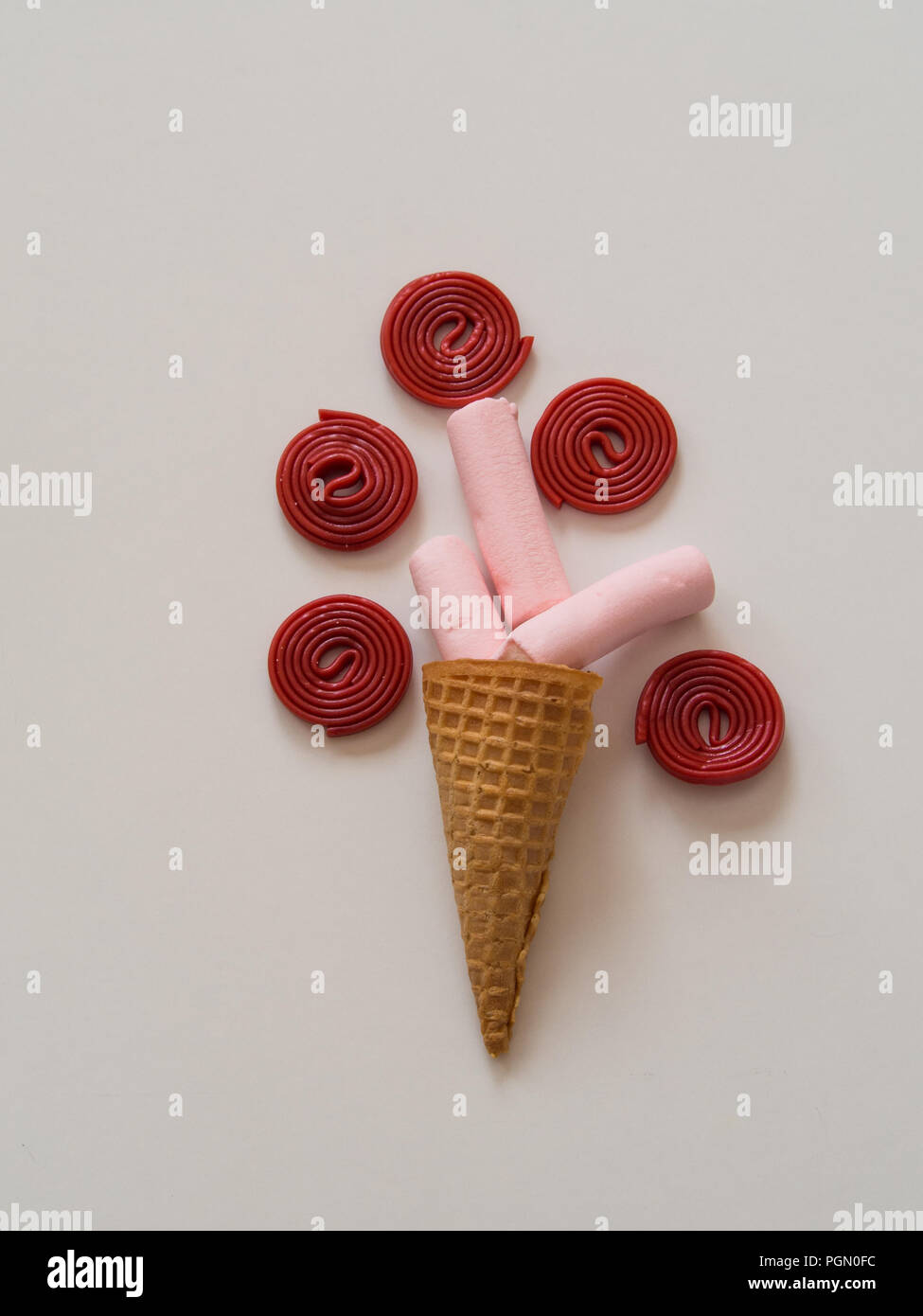Composition of marshmallow in ice cream cone and licorice on white