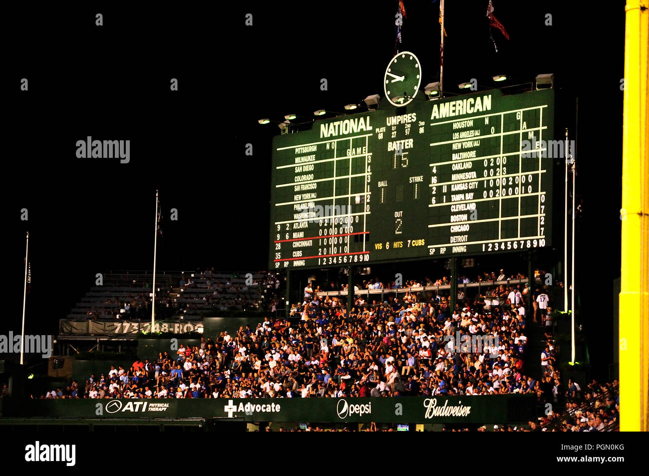 SPORTS Chicago Illinois Night game at Wrigley Field fans in bleachers  traditional scoreboard ivy on outfield wall Stock Photo - Alamy