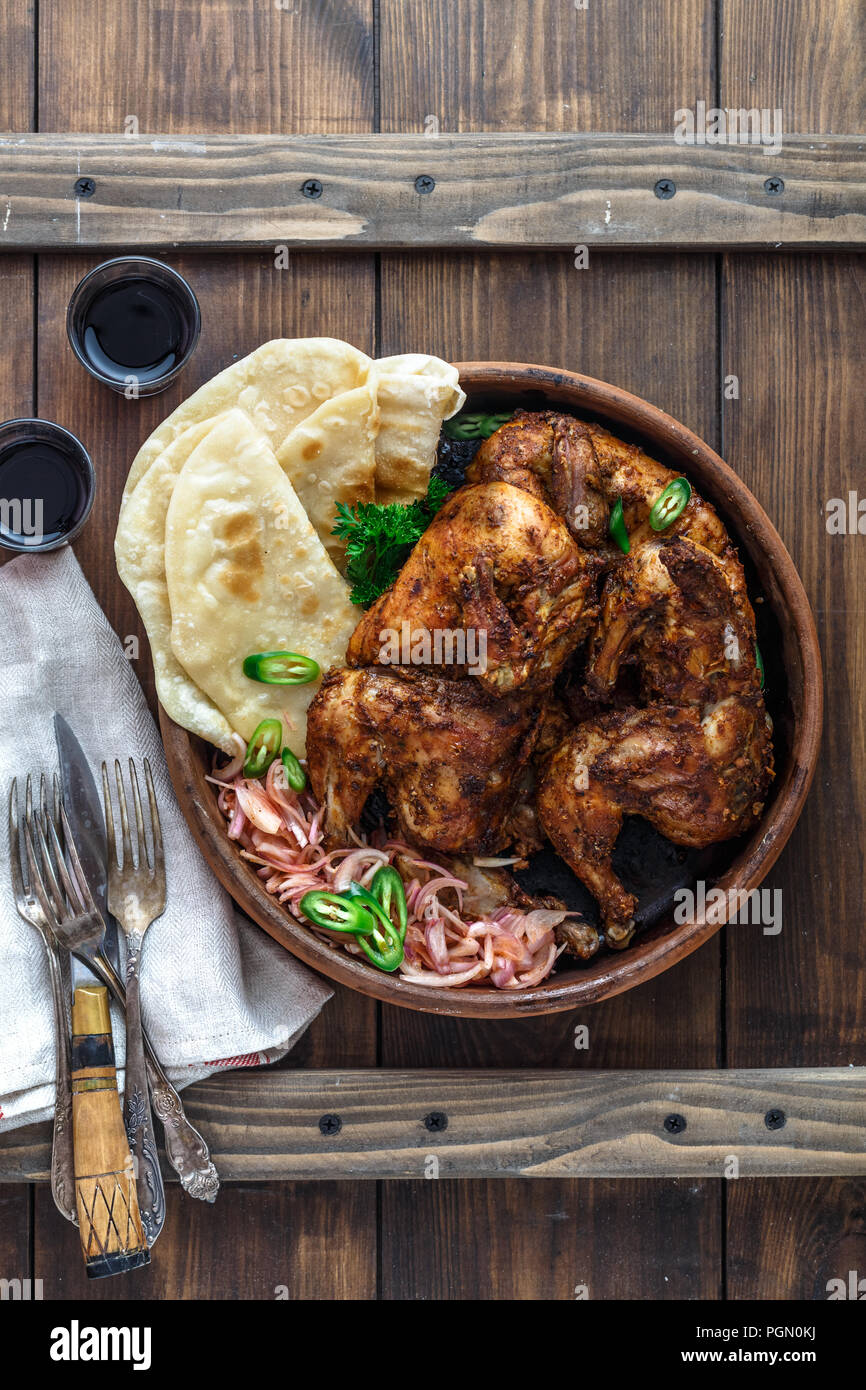 Tandoori chicken. Half of tandoori chicken served with lime slices and cilantro. Top view, blank space Stock Photo