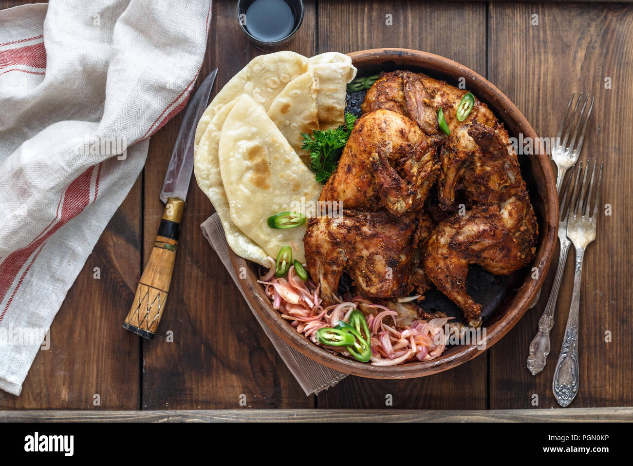 Tandoori chicken. Half of tandoori chicken served with lime slices and cilantro. Top view, blank space Stock Photo