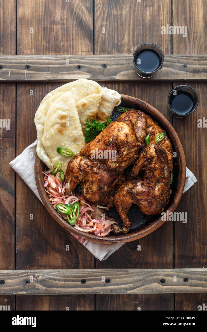 Tandoori chicken. Half of tandoori chicken served with lime slices and cilantro. Top view, blank space Stock Photo