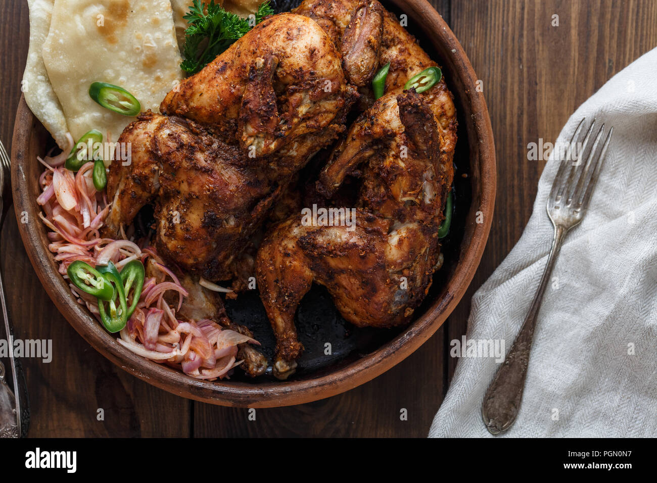 Tandoori chicken. Half of tandoori chicken served with lime slices and cilantro. Top view, blank space Stock Photo