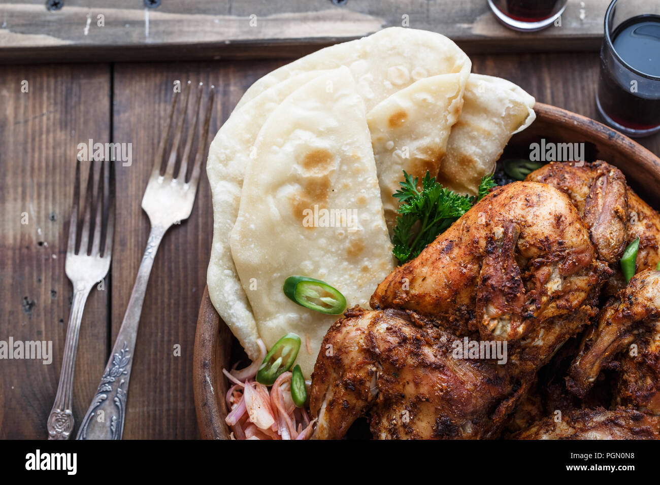 Tandoori chicken. Half of tandoori chicken served with lime slices and cilantro. Top view, blank space Stock Photo
