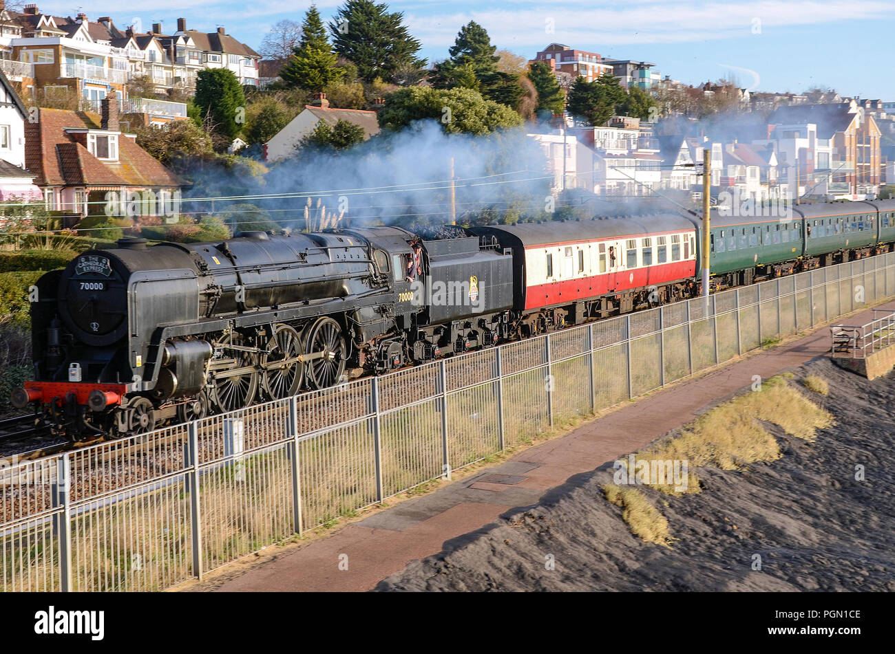 Britannia steam locomotive hauling a steam special from Southend, Essex at Chalkwell beach on C2C line by Thames Estuary. 70000 in black scheme Stock Photo