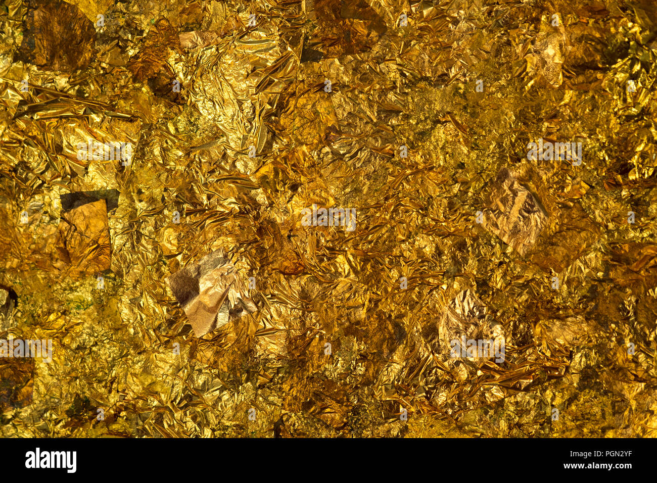 Shiny yellow gold leaf or scraps of gold foil background texture, surface  from Back of Buddha image Stock Photo - Alamy