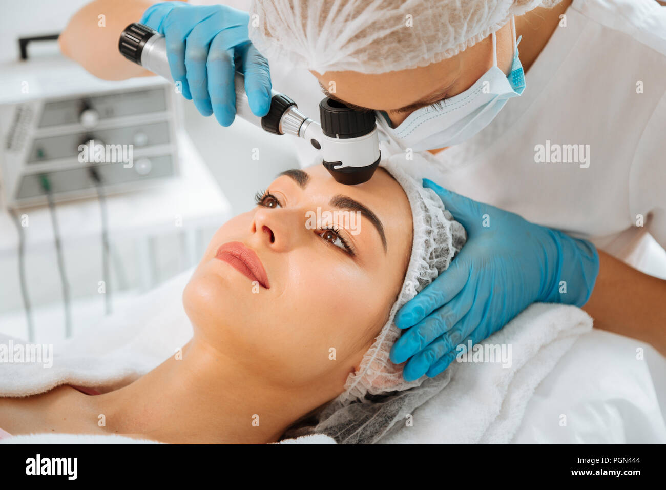 Skilled female dermatologist using modern professional equipment Stock Photo