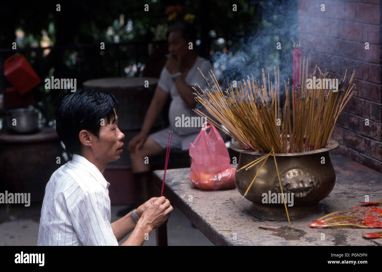 Chinese man ancestral worshipping with incense in a temple in Hong Kong Stock Photo