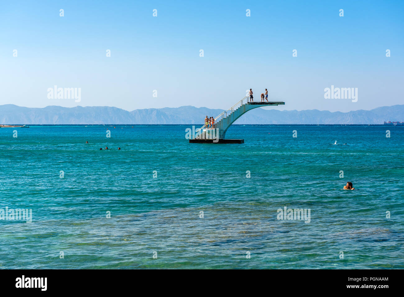 RHODES, GREECE - May 13, 2018: Young people on a sea diving platform. Elli beach, the main beach of Rhodes town. Greece Stock Photo