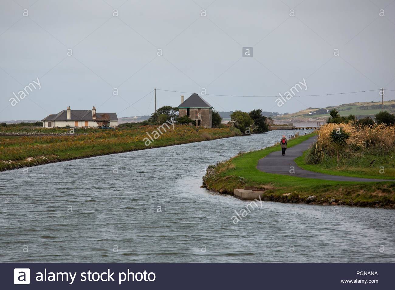 A woman walking along the water's edge by a canal in Tralee <County Kerry Ireland Stock Photo