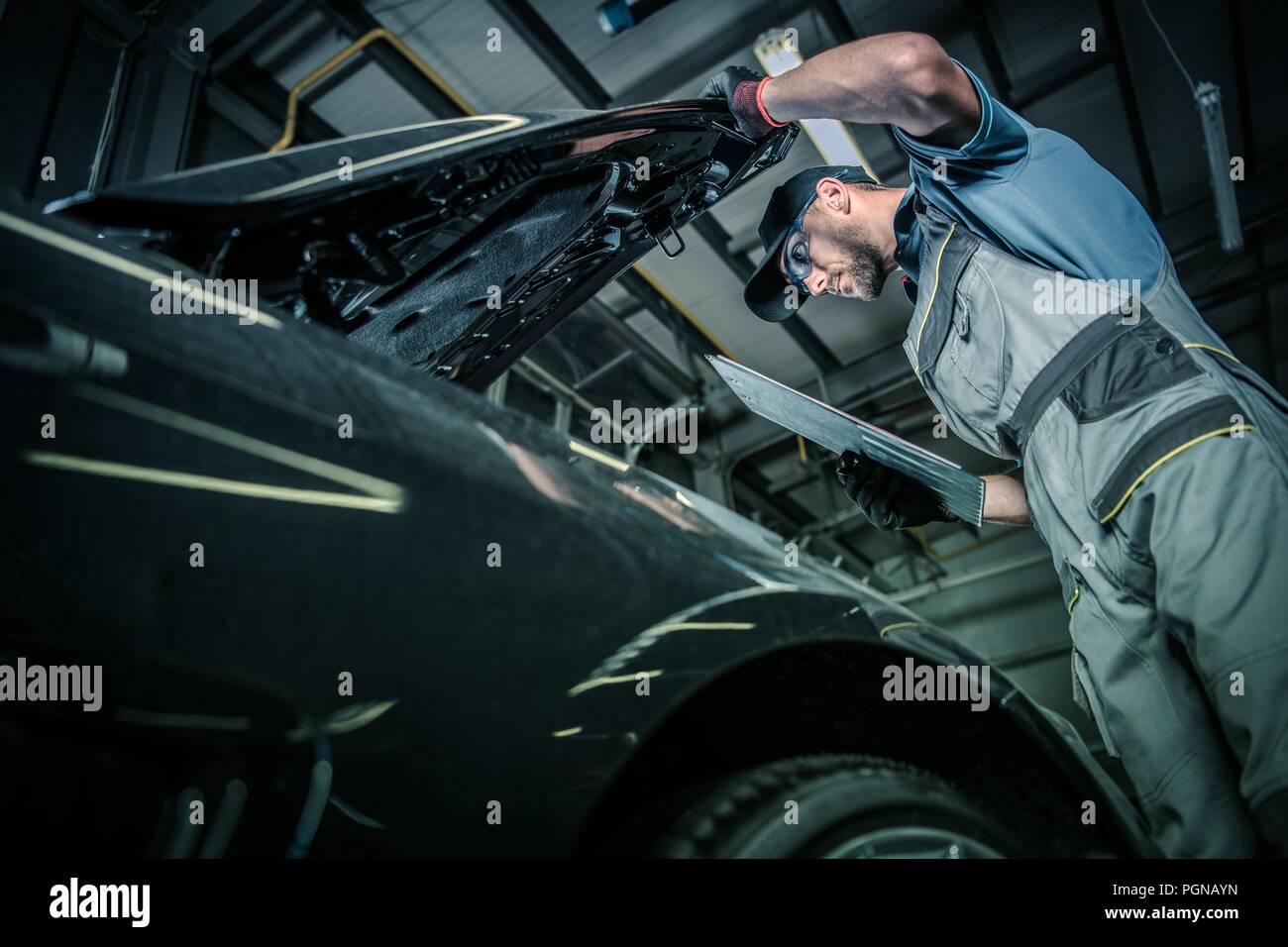 Servicing Modern Car. Pre Owned Vehicle Inside Auto Service. Caucasian Car Mechanic in His 30s Taking Look Under the Hood. Automotive Theme. Stock Photo