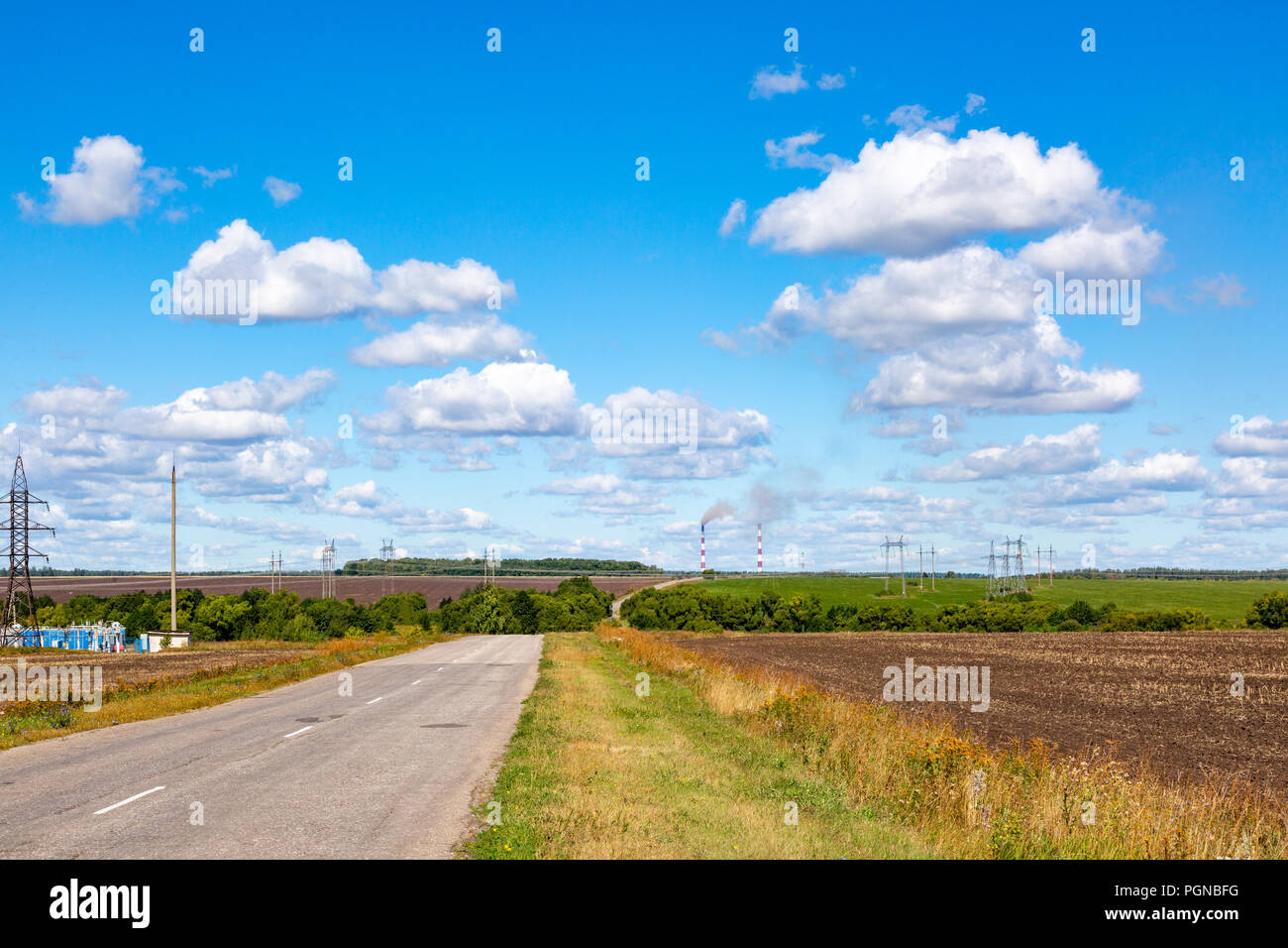 asphalt road through the green field and clouds on blue sky in summer ...