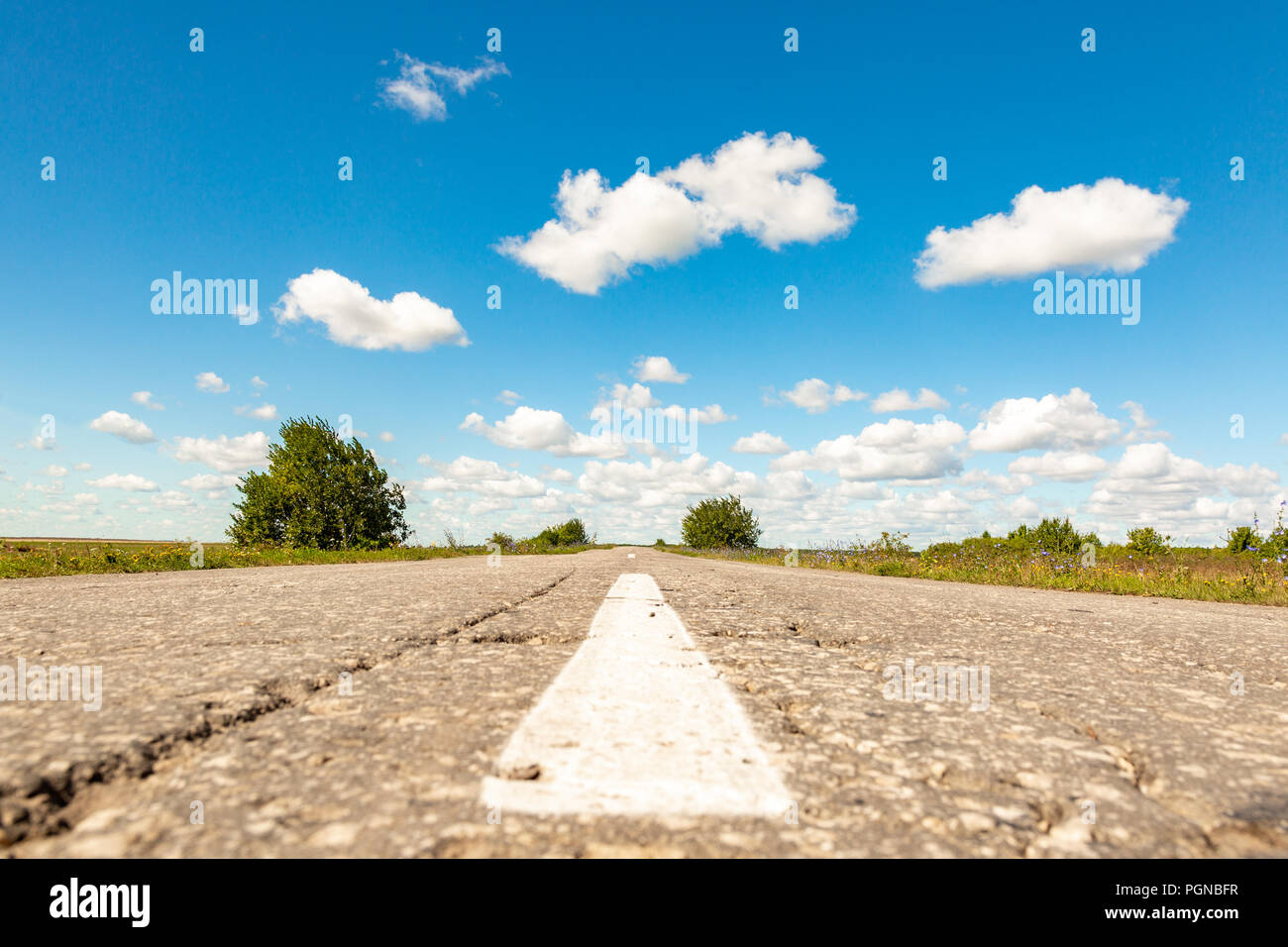 asphalt road through the green field and clouds on blue sky in summer ...