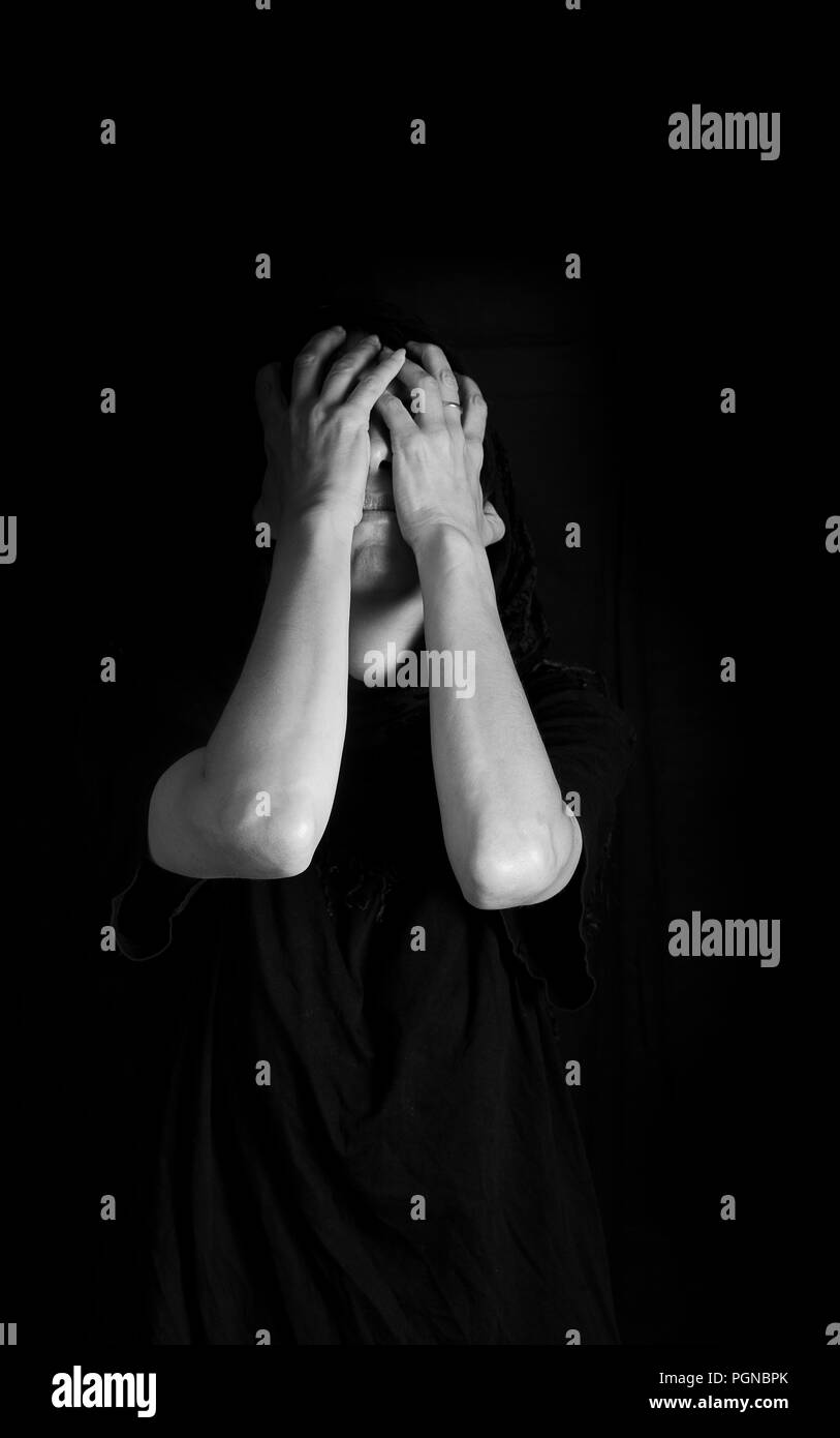 Black and white monochrome image of woman with covered face - concept of sorrow and guilt Stock Photo