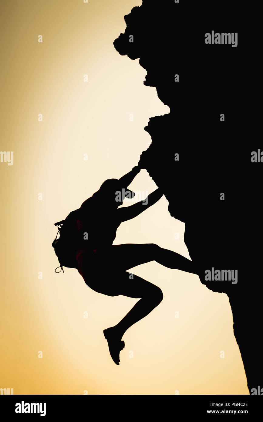 Athletic person silhouette climbing a vertical rock. Adventure and challenge concept Stock Photo