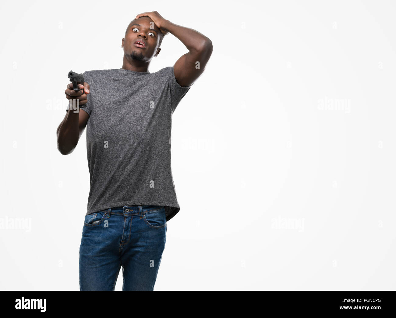 Young african american man holding a gun stressed with hand on head, shocked with shame and surprise face, angry and frustrated. Fear and upset for mi Stock Photo