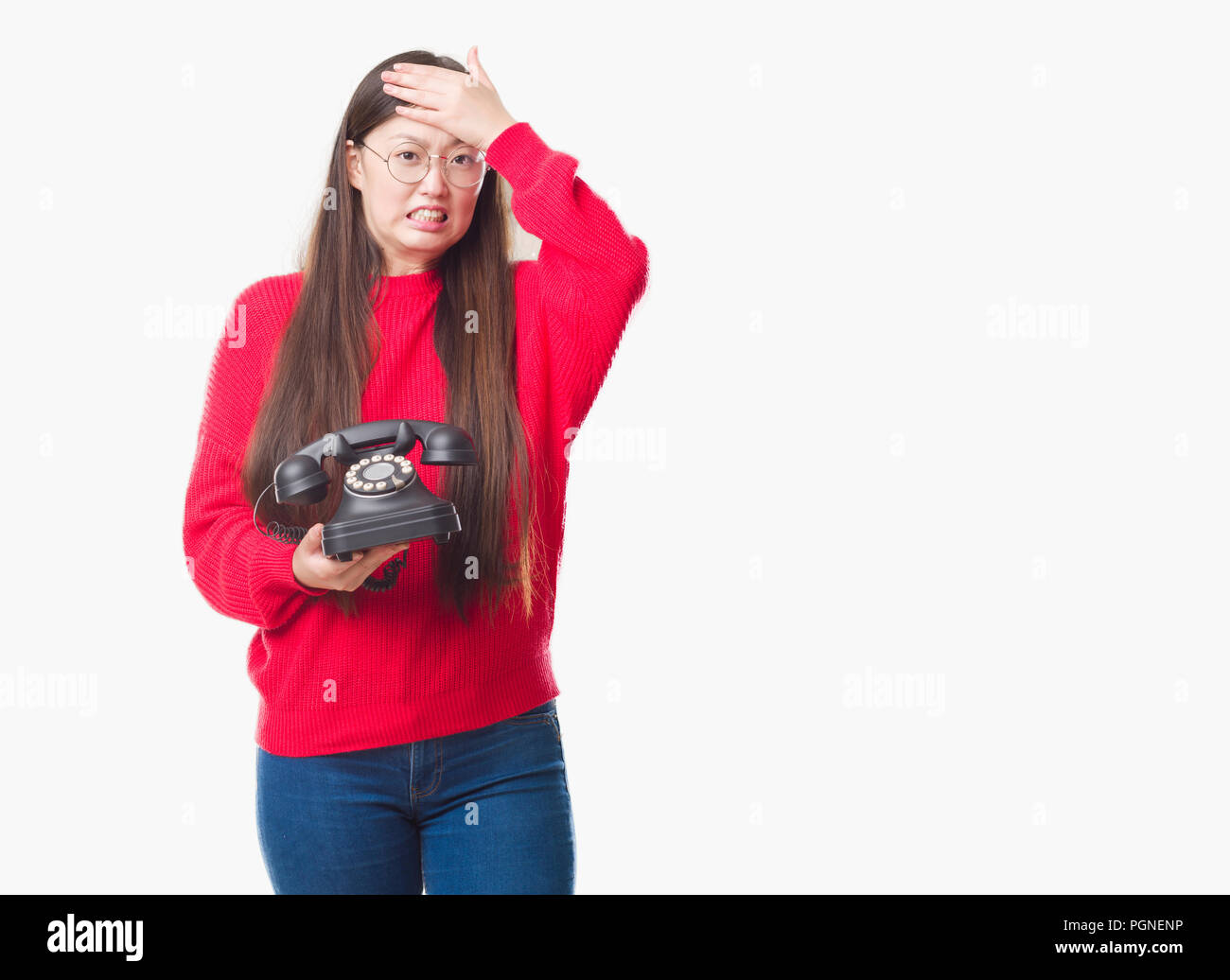 Young Chinese woman over isolated background holding vintage telephone stressed with hand on head, shocked with shame and surprise face, angry and fru Stock Photo