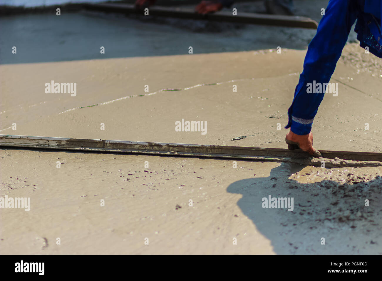 Masonry Worker Is Using Long Trowel To Smooth Or Leveling Concrete