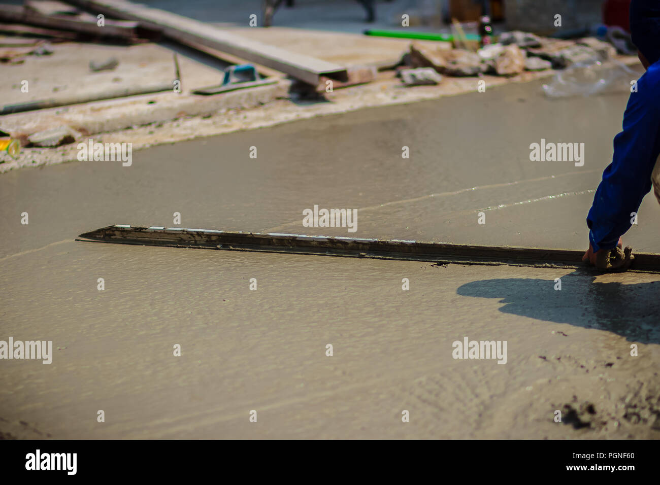 Masonry worker is using long trowel to smooth or leveling concrete flooring work step of the