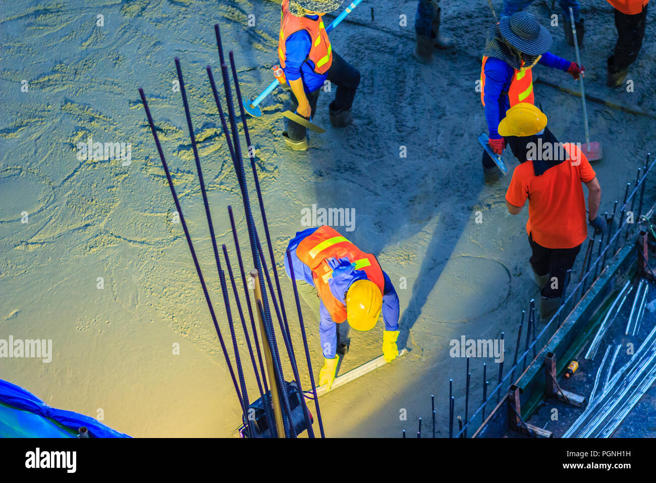 Mason worker leveling concrete with trowels, mason hands spreading poured concrete. Concreting workers are leveling poured liquid concrete on a steel  Stock Photo