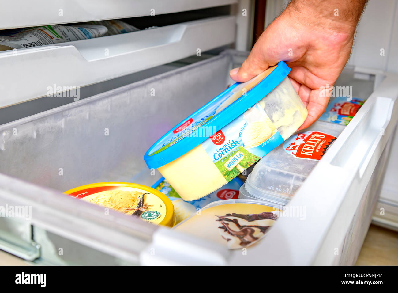 Mans hand getting out an ice cream tub from a home freezer Stock Photo