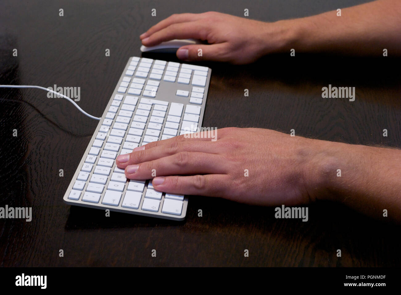 Typing and Using Mouse on a Desk with Mouse and Keyboard Stock Photo