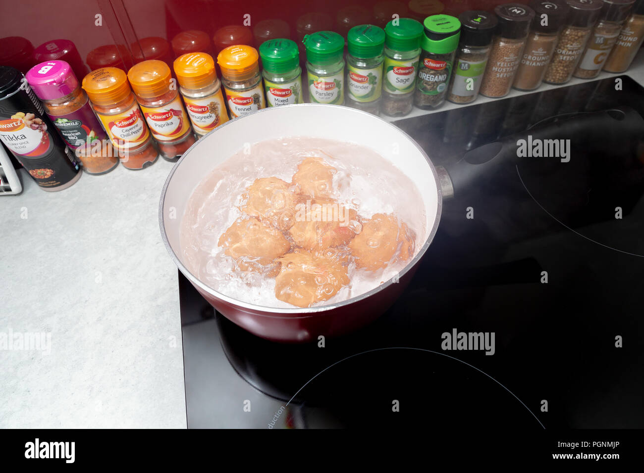 Six eggs boiling in a saucepan on an Induction Hob Stock Photo