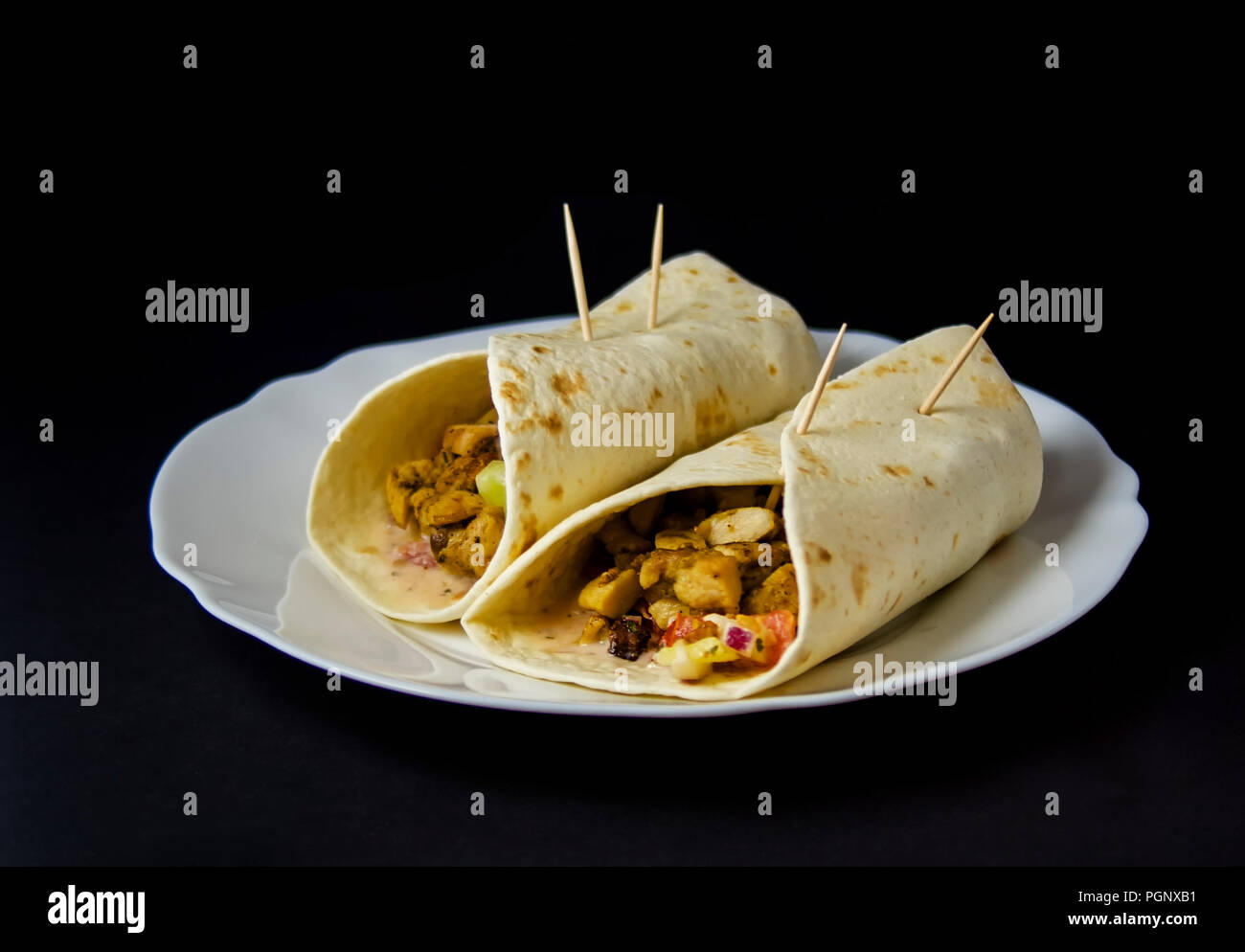 Homemade Burrito with chicken and vegetables isolated on black background.Burritos are a