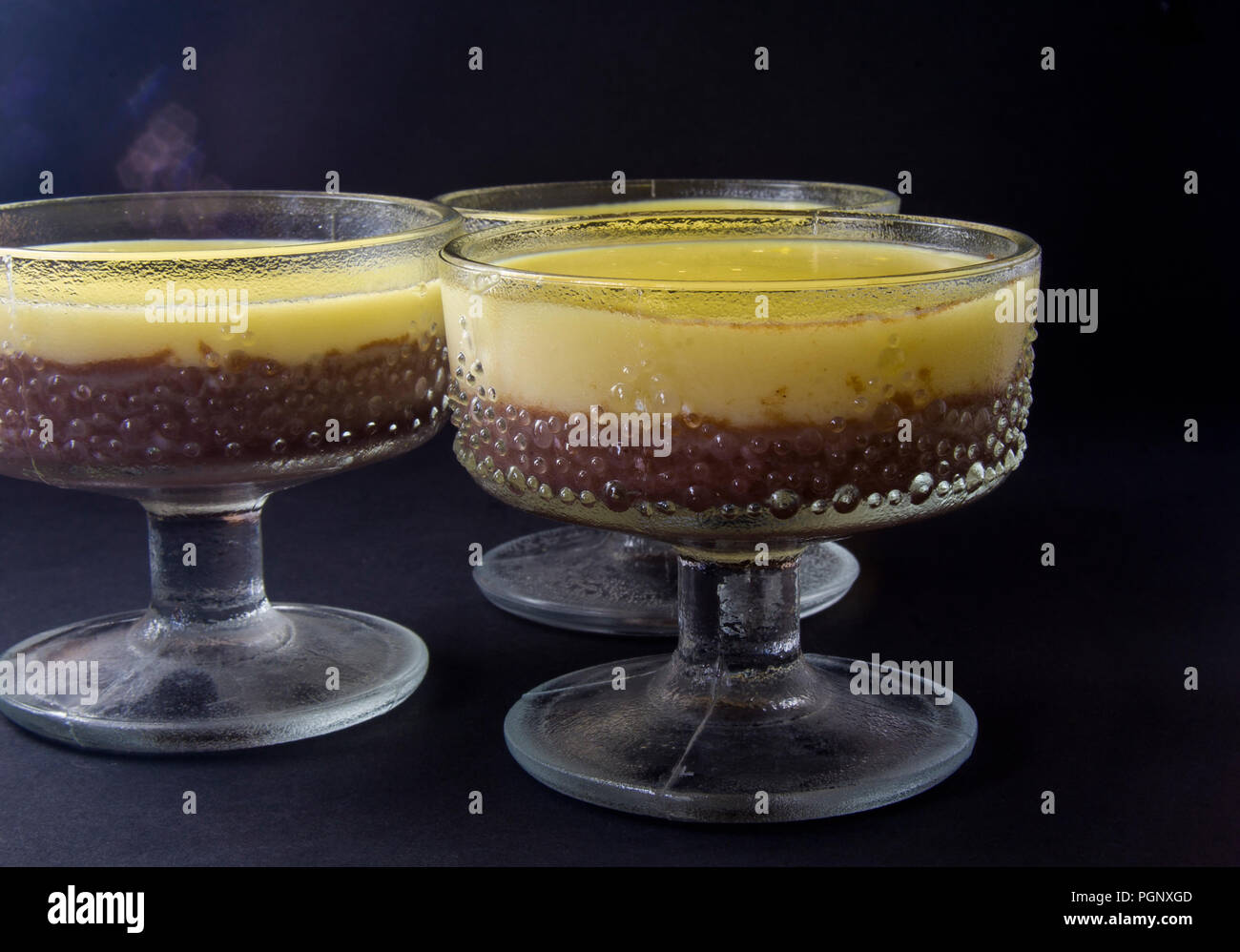 Mousse, souffle, pudding with vanilla and chocolate in glass black, dark background. Stock Photo