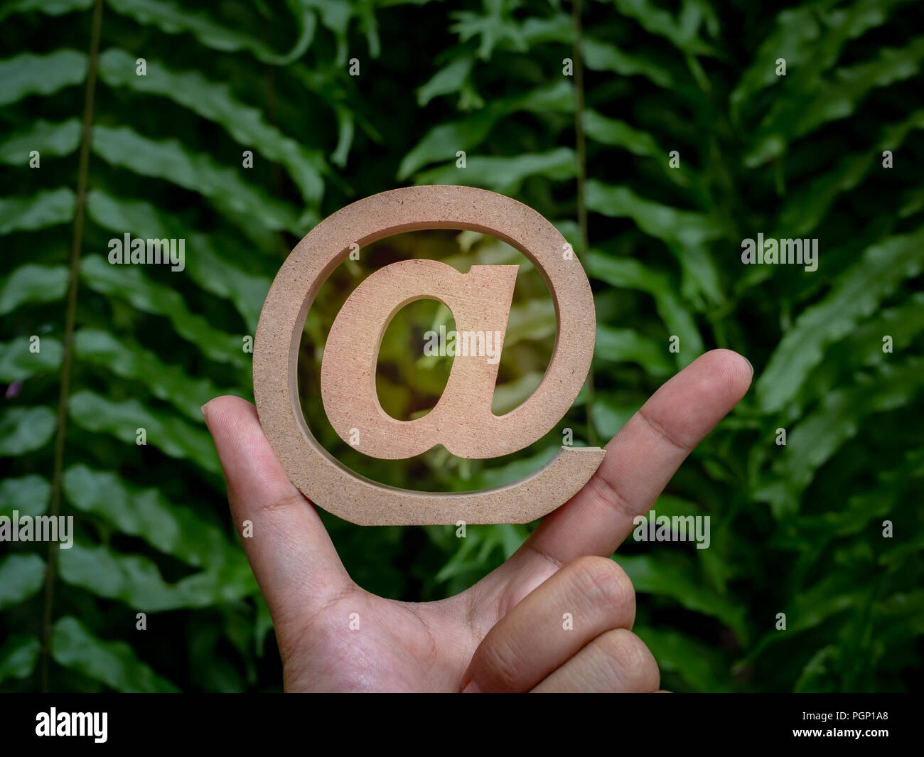 Wooden Email address symbol on correct pointing hand sign, arroba icon