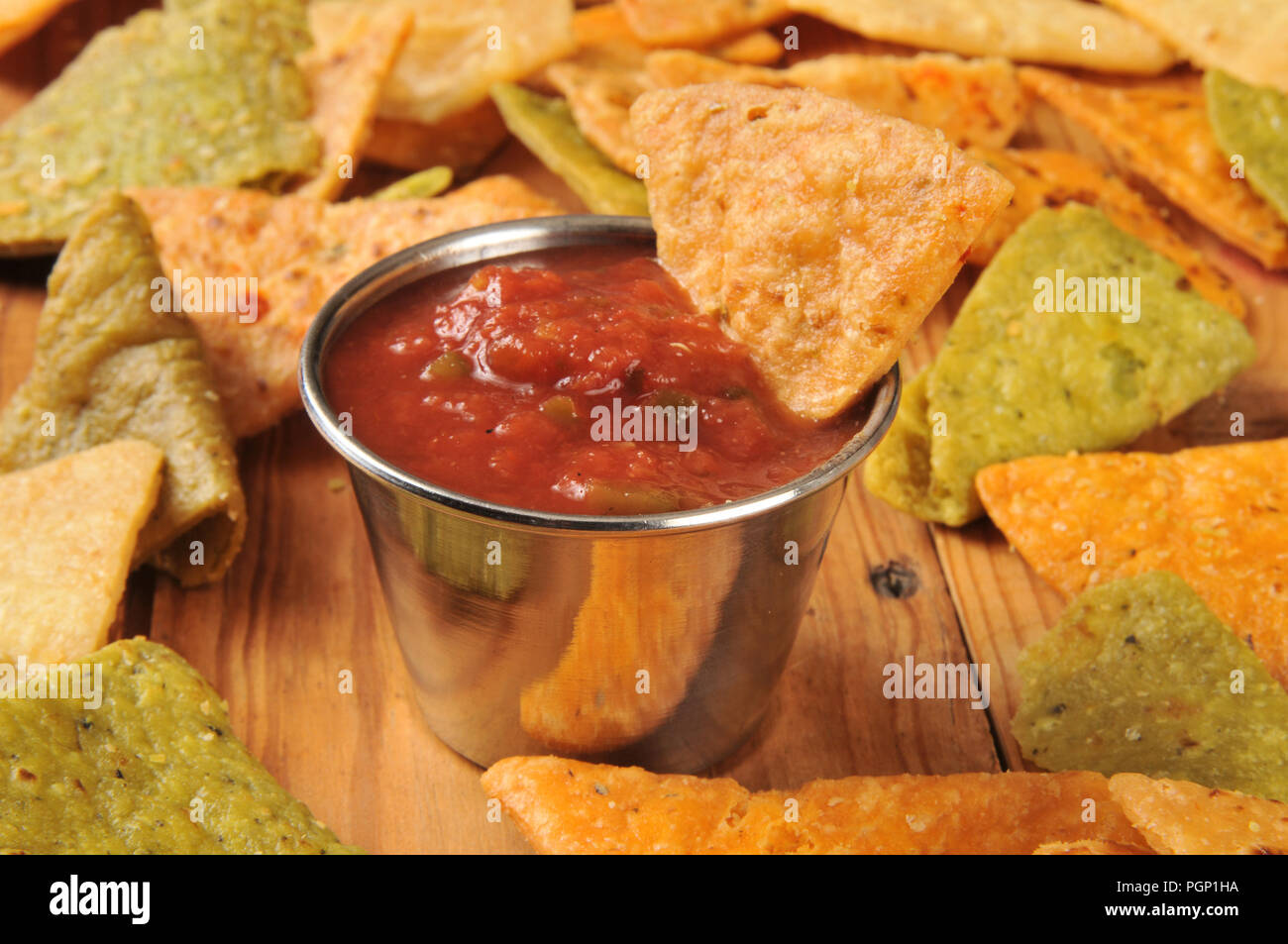 Vegetable tortilla chips with a dish of salsa on a wooden surface Stock