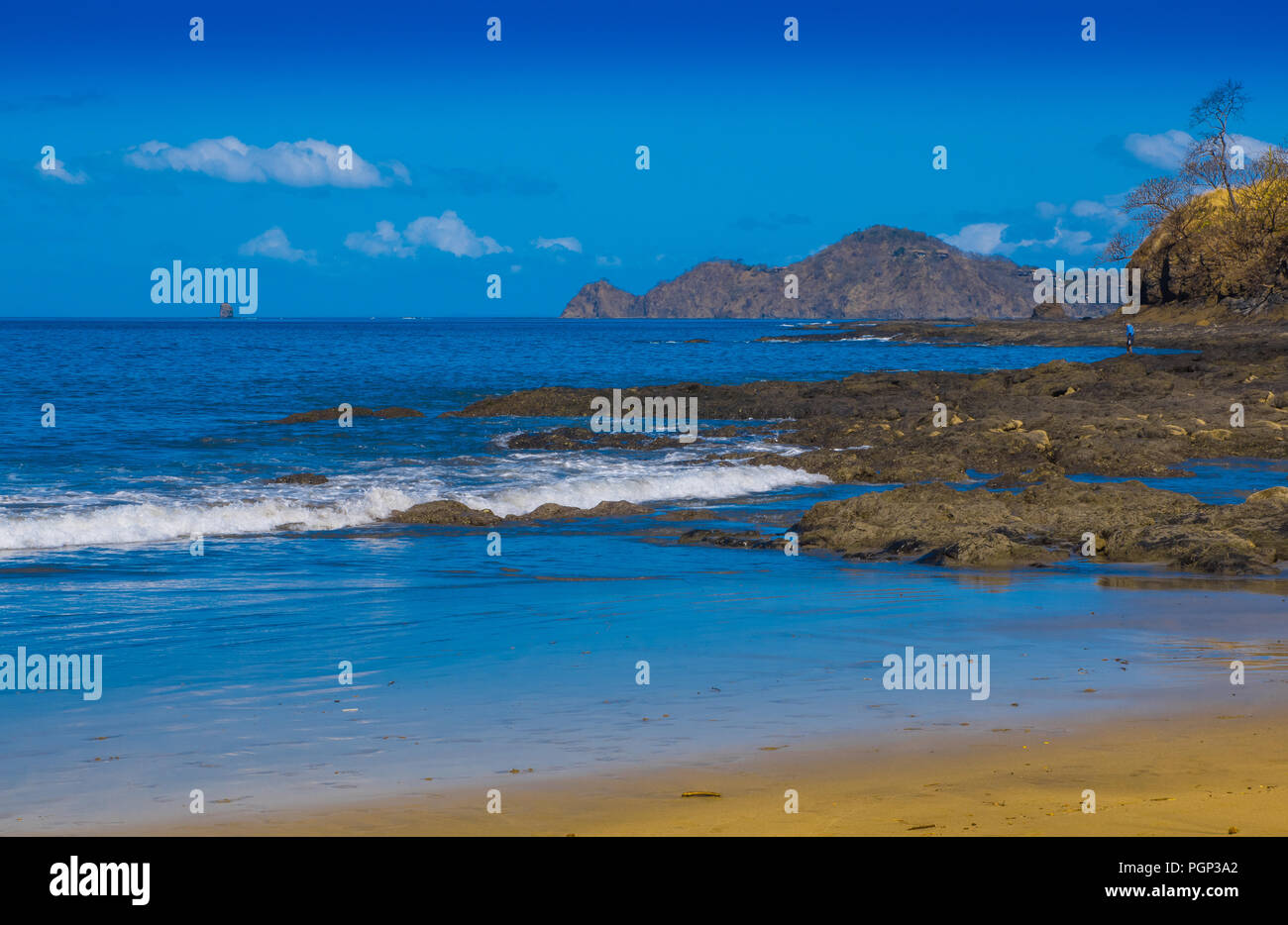 Beautiful outdoor view of of gorgeous rocky beach in Playa hermosa with blue water and beautiful sunny day with blue sky in Costa Rica. Stock Photo