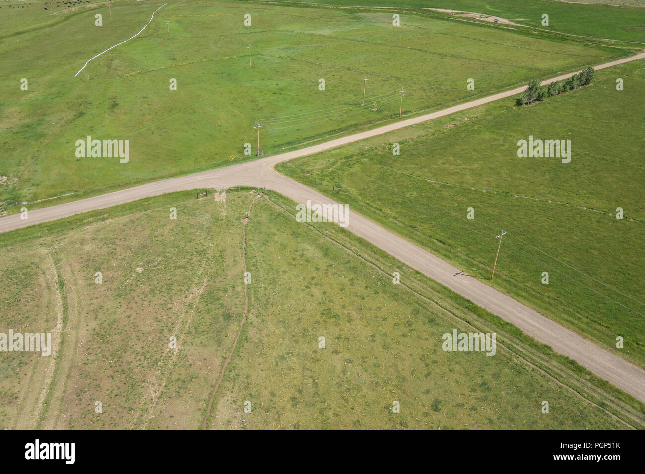 Intersection of dirt and gravel farming roads between green fields in the American midwest. Stock Photo