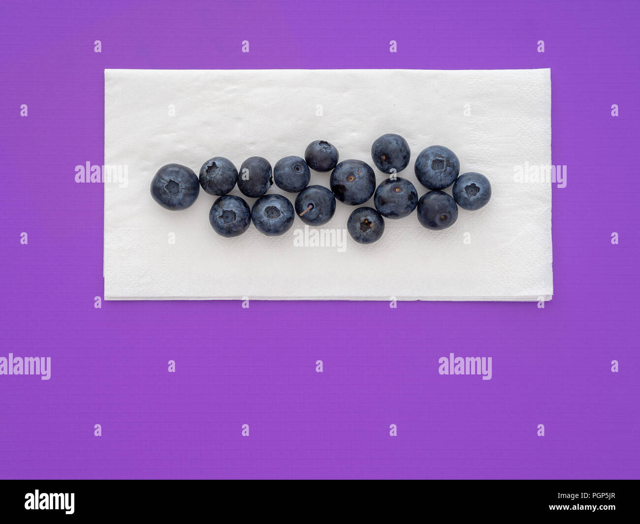 Healthy superfood blueberries on white paper napkin, serviette, on purple background. With copyspace. Stock Photo