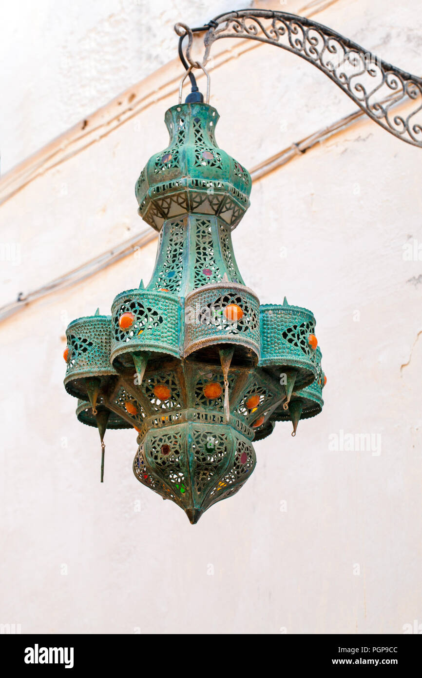 Moroccan vintage pierced metal hanging lantern exterior light fixture. Green verdigris studded with orange cabochons. Location: Essaouira, Morocco Stock Photo