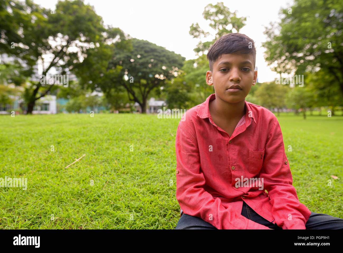 Portrait of young Indian boy relaxing at the park Stock Photo