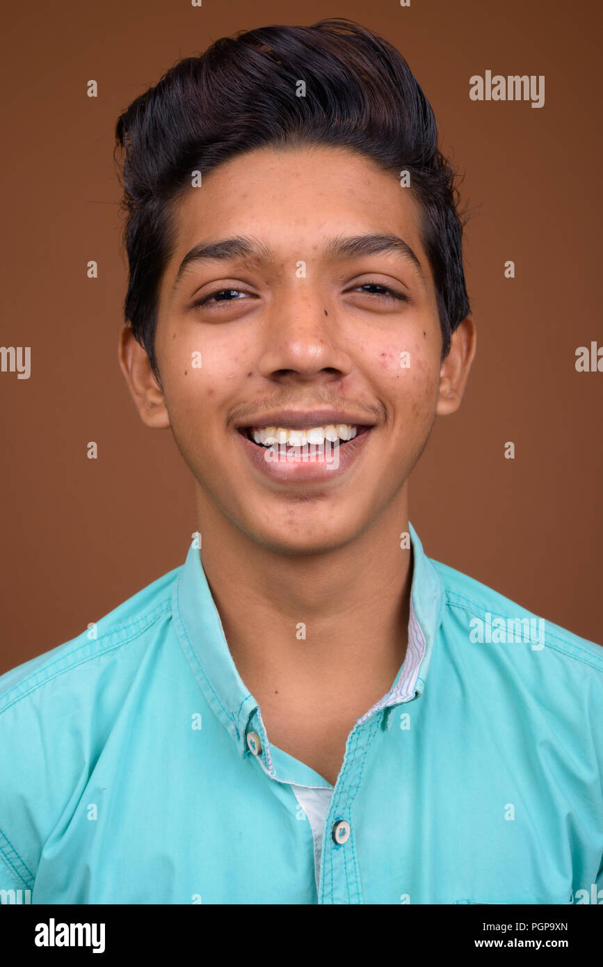 Young Indian boy wearing blue shirt looking smart against brown Stock ...