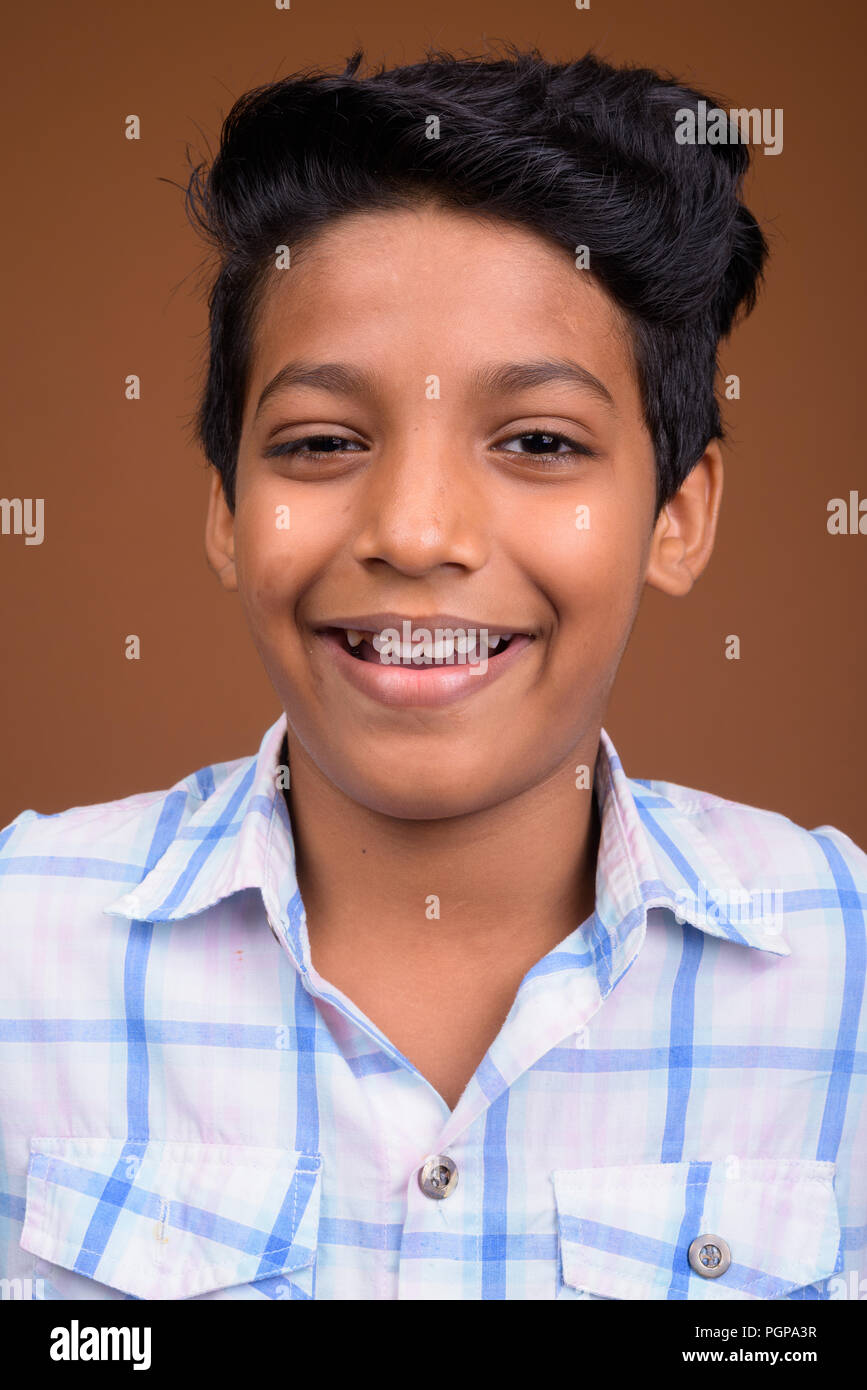 Young Indian boy wearing checkered shirt against brown backgroun Stock Photo