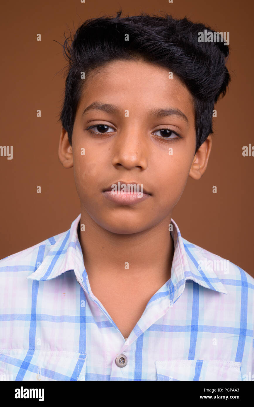 Young Indian boy wearing checkered shirt against brown backgroun Stock Photo
