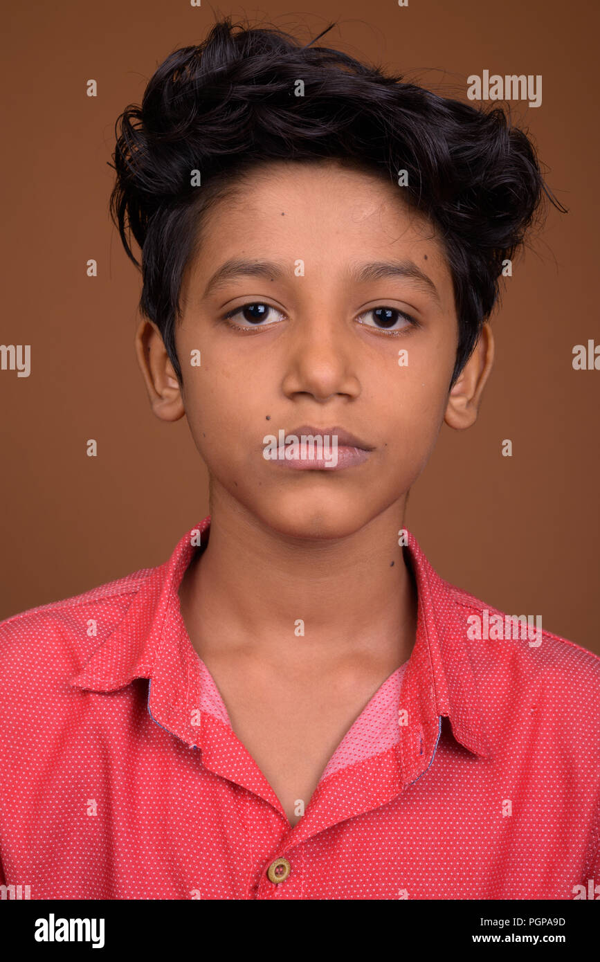 Young Indian boy wearing smart casual clothing against brown bac Stock Photo