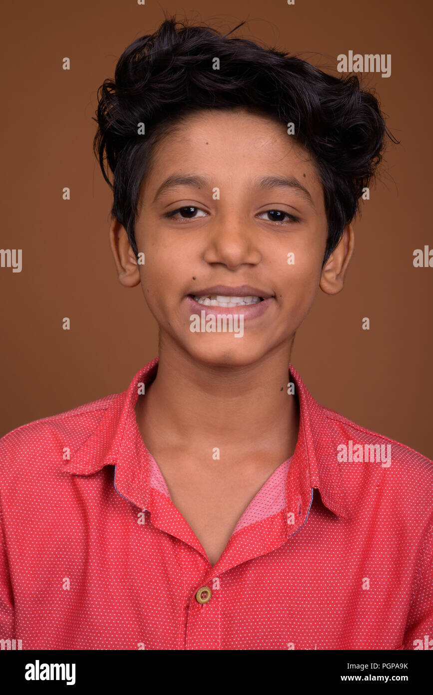 Young Indian boy wearing smart casual clothing against brown bac Stock Photo