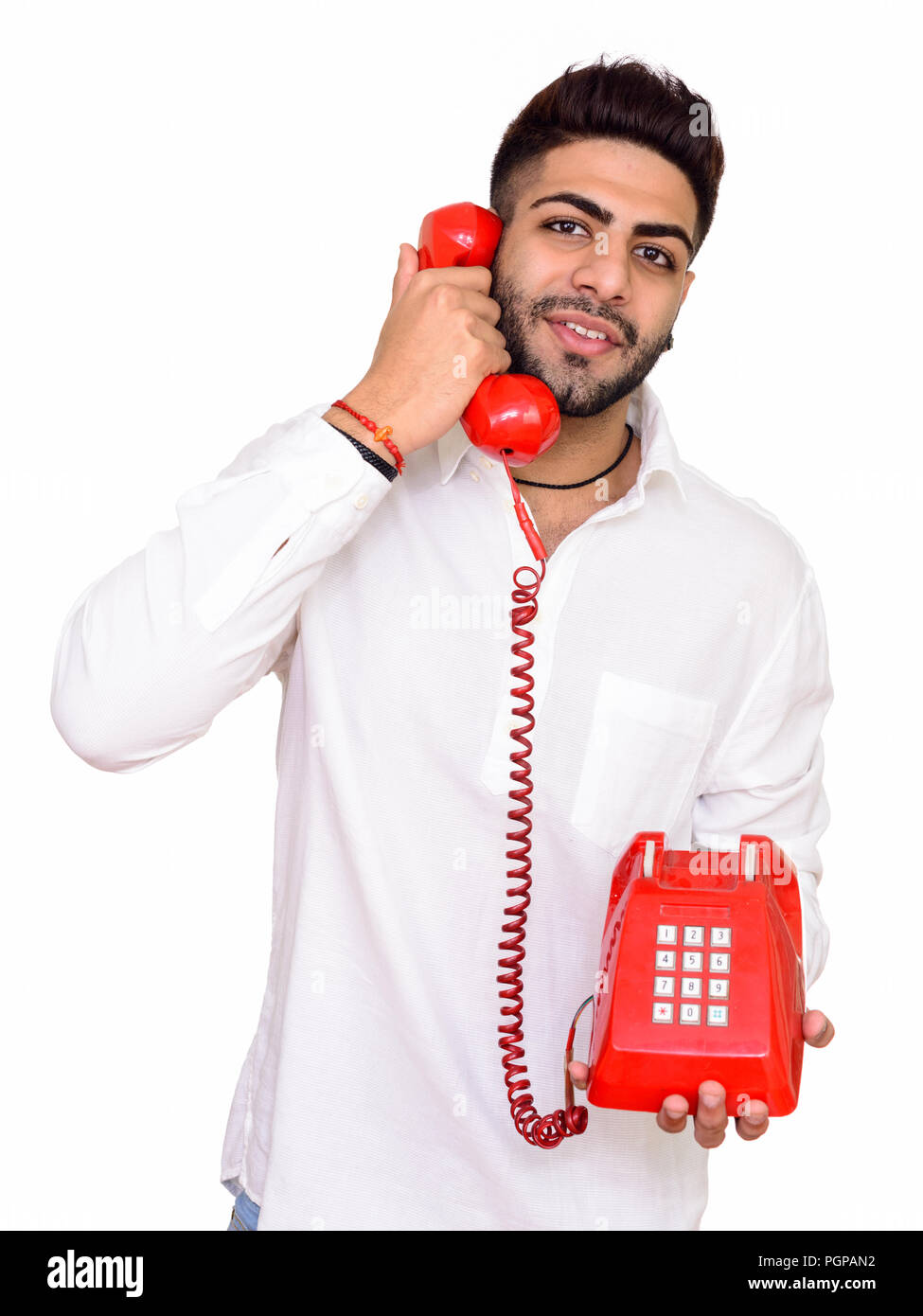 Studio shot of young happy Indian man talking on telephone isola Stock Photo