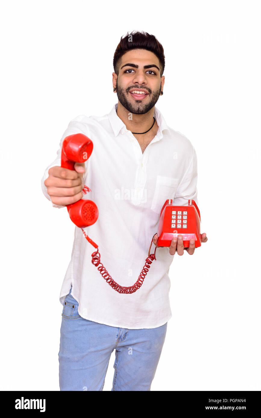 Studio shot of young happy Indian man giving telephone isolated  Stock Photo